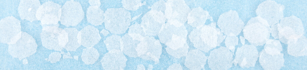 Fototapeta na wymiar White round plastic foam sheet pieces on blue background. Winter snowfall concept. Torn foam polyethylene transparent pieces as snowflakes.