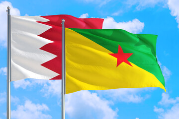 French Guiana and Bahrain national flag waving in the windy deep blue sky. Diplomacy and international relations concept.