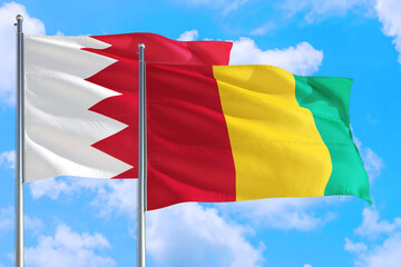 Guinea Bissau and Bahrain national flag waving in the windy deep blue sky. Diplomacy and international relations concept.