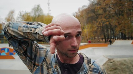 European young bald man holding skateboard and smiling, portrait of happy skater in skatepark, caucasian male professional skateboarder, generation z student lifestyle, professional sport