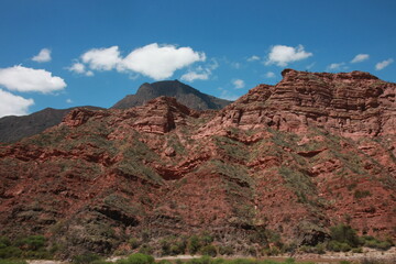 A large hill in a mountainous area that is coverd by large red boulders and rocks in Peru