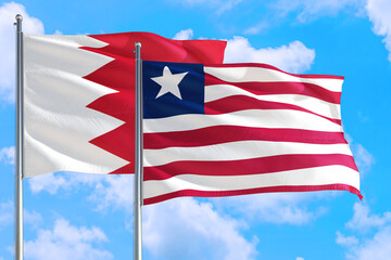 Liberia and Bahrain national flag waving in the windy deep blue sky. Diplomacy and international relations concept.
