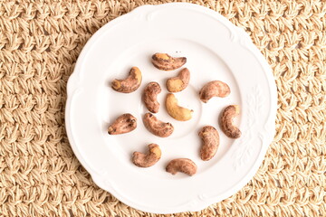 Fragrant roasted salted cashews on a straw mat, close-up.
