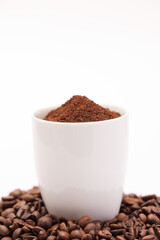 white ceramic cup with coffee powder inside, with coffee beans and white background