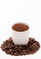 white ceramic cup with coffee powder inside, with coffee beans and white background