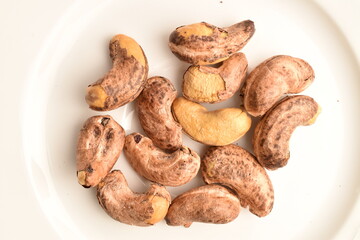 Obraz premium Fragrant fried salted cashews, close-up, on a white ceramic dish.