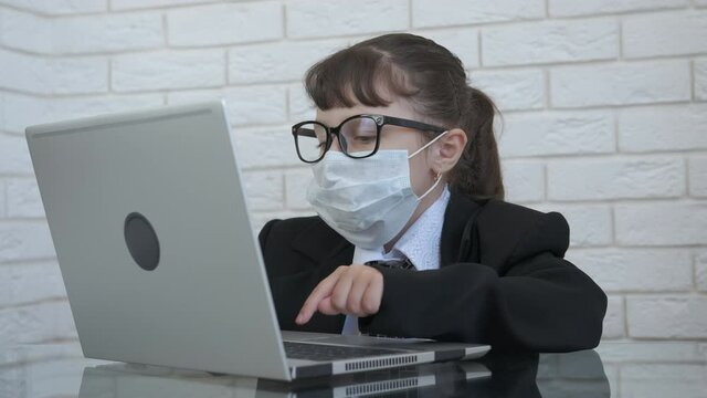 Business child in a mask. End of quarantine concept. Happy little girl in a business suit takes off the protective mask.
