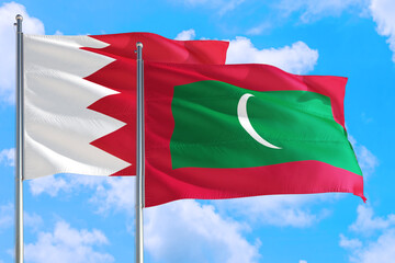 Maldives and Bahrain national flag waving in the windy deep blue sky. Diplomacy and international relations concept.