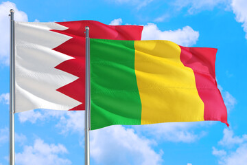 Mali and Bahrain national flag waving in the windy deep blue sky. Diplomacy and international relations concept.