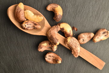 Several roasted cashews, close-up, on a slate board.