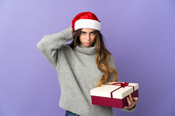 Girl with christmas hat holding a present isolated on white background having doubts