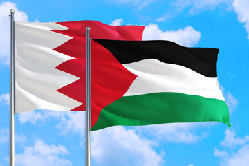 Palestine and Bahrain national flag waving in the windy deep blue sky. Diplomacy and international relations concept.