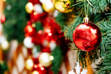 Closeup of Festively Decorated Outdoor Christmas tree with bright red balls on blurred background.