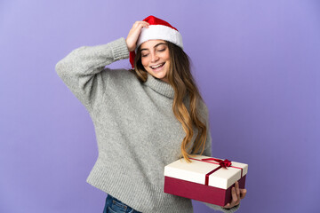 Girl with christmas hat holding a present isolated on white background smiling a lot