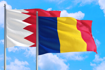 Romania and Bahrain national flag waving in the windy deep blue sky. Diplomacy and international relations concept.
