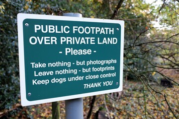 Sign saying public footpath over private land, please take nothing but photographs, leave nothing but footprints, keep dogs under close control, thank you