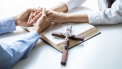 Christian woman praying with hands together on holy bible and wooden cross. Woman pray for god blessing to wishing have a better life and believe in goodness.