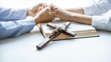 Christian woman praying with hands together on holy bible and wooden cross. Woman pray for god blessing to wishing have a better life and believe in goodness.