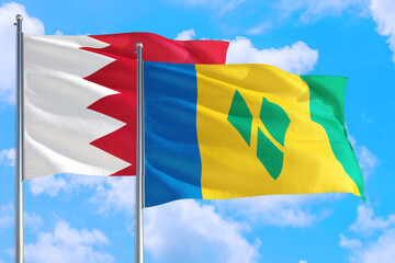 Saint Vincent And The Grenadines and Bahrain national flag waving in the windy deep blue sky. Diplomacy and international relations concept.