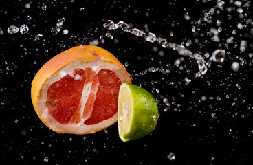 Fototapeta na wymiar citrus fruits in water splash on black background