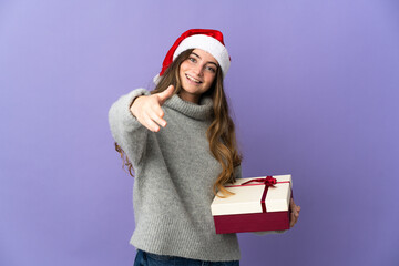 Girl with christmas hat holding a present isolated on white background shaking hands for closing a good deal