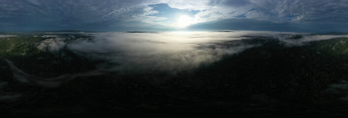 Fototapeta na wymiar Aerial panoramic view over a tropical rainforest seen from above the clouds during sunrise