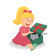 A girl in a pink dress opens a Christmas gift with a cat in a box.