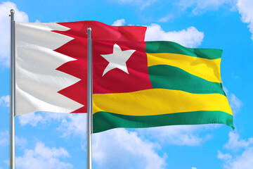 Togo and Bahrain national flag waving in the windy deep blue sky. Diplomacy and international relations concept.