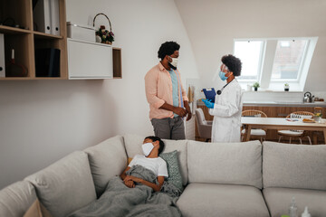 Obraz premium Female doctor visiting father and son at home
