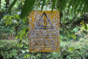 Old and with white moss overgrown sign warning for deep water