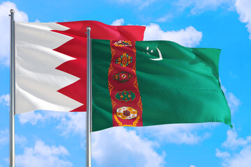 Turkmenistan and Bahrain national flag waving in the windy deep blue sky. Diplomacy and...