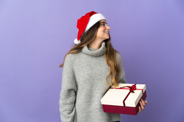 Girl with christmas hat holding a present isolated on white background laughing in lateral position