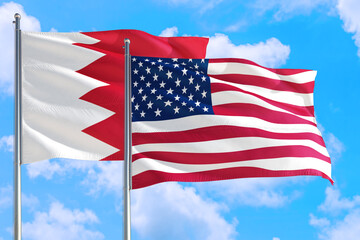 United States and Bahrain national flag waving in the windy deep blue sky. Diplomacy and international relations concept.