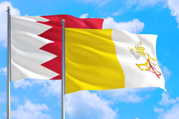 Vatican City and Bahrain national flag waving in the windy deep blue sky. Diplomacy and international relations concept.