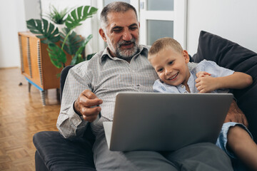 grandfather and his grandson using computer at home