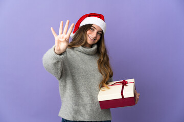 Girl with christmas hat holding a present isolated on white background happy and counting four with fingers