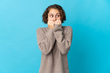 Young English woman isolated on blue background nervous and scared putting hands to mouth