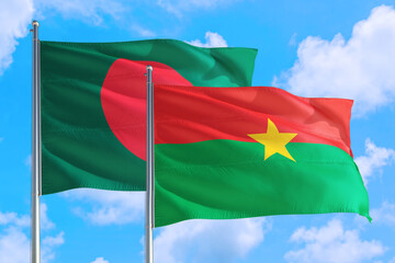 Burkina Faso and Bangladesh national flag waving in the windy deep blue sky. Diplomacy and international relations concept.