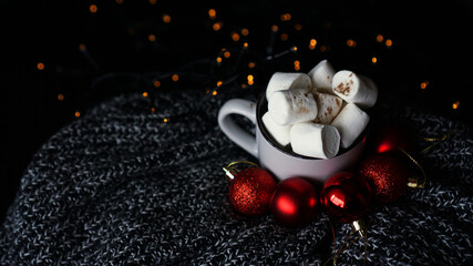 Mug of hot chocolate with marshmallow on a dark background, winter Christmas hot drink with red christmas balls and bokeh lights