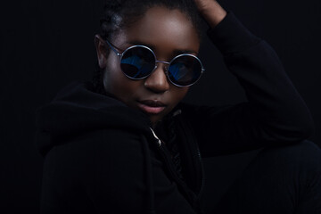 Close-up of cool woman with dark skin wearing round sunglasses