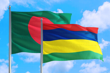 Mauritius and Bangladesh national flag waving in the windy deep blue sky. Diplomacy and international relations concept.