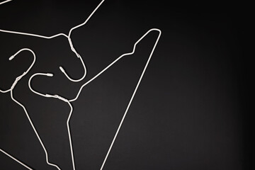 Empty white hangers lying on black background