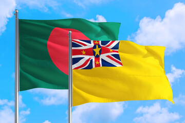 Niue and Bangladesh national flag waving in the windy deep blue sky. Diplomacy and international relations concept.