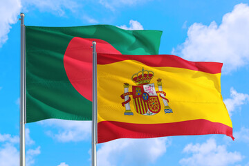 Spain and Bangladesh national flag waving in the windy deep blue sky. Diplomacy and international relations concept.
