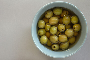 green olives in a gray plate on a gray background. Mediterranean cuisine