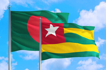 Togo and Bangladesh national flag waving in the windy deep blue sky. Diplomacy and international relations concept.