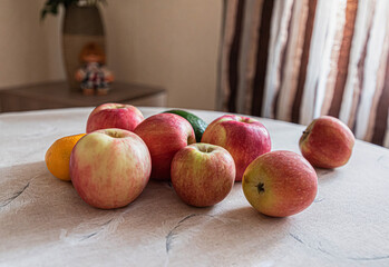 Juicy and tasty red apples, mandarin and avocado are at the dinner table.