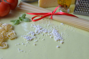 composition of healthy food ingredients on white background, top view. Ingredients for making macron, spaghetti, pasta. Tomatoes, basil, parmesan cheese, grater