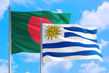 Uruguay and Bangladesh national flag waving in the windy deep blue sky. Diplomacy and international relations concept.