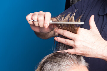 Hairdresser trimming brown hair with scissors